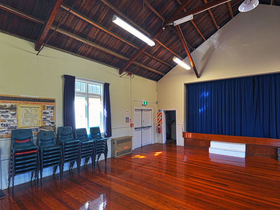 Hall interior with timber ceiling, polished timber floor, and blue curtained stage