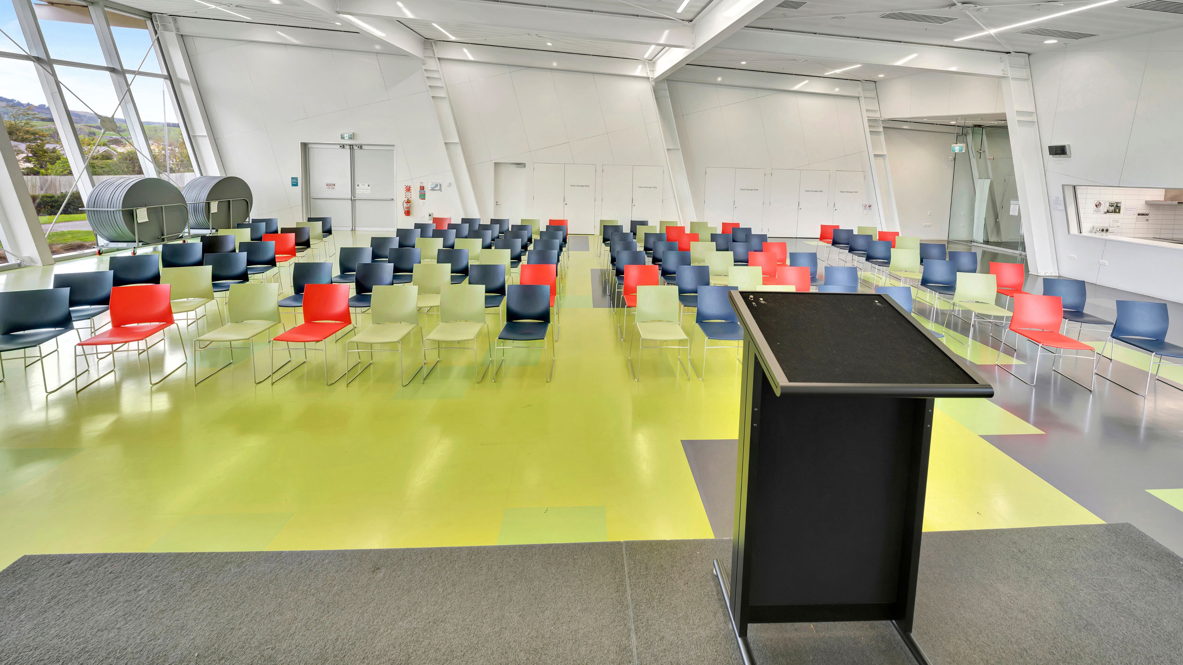 Large hall with coloured seating rows, lectern and angled ceiling