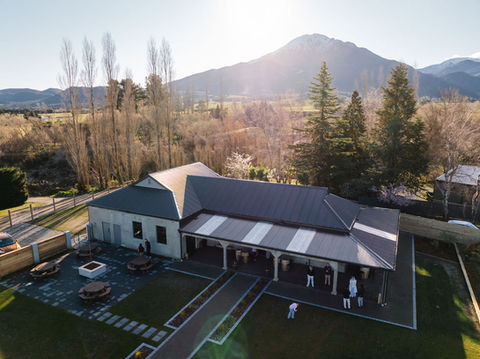 Aerial view of venue buildings, lawn, outdoor seating, and surrounding trees with mountain