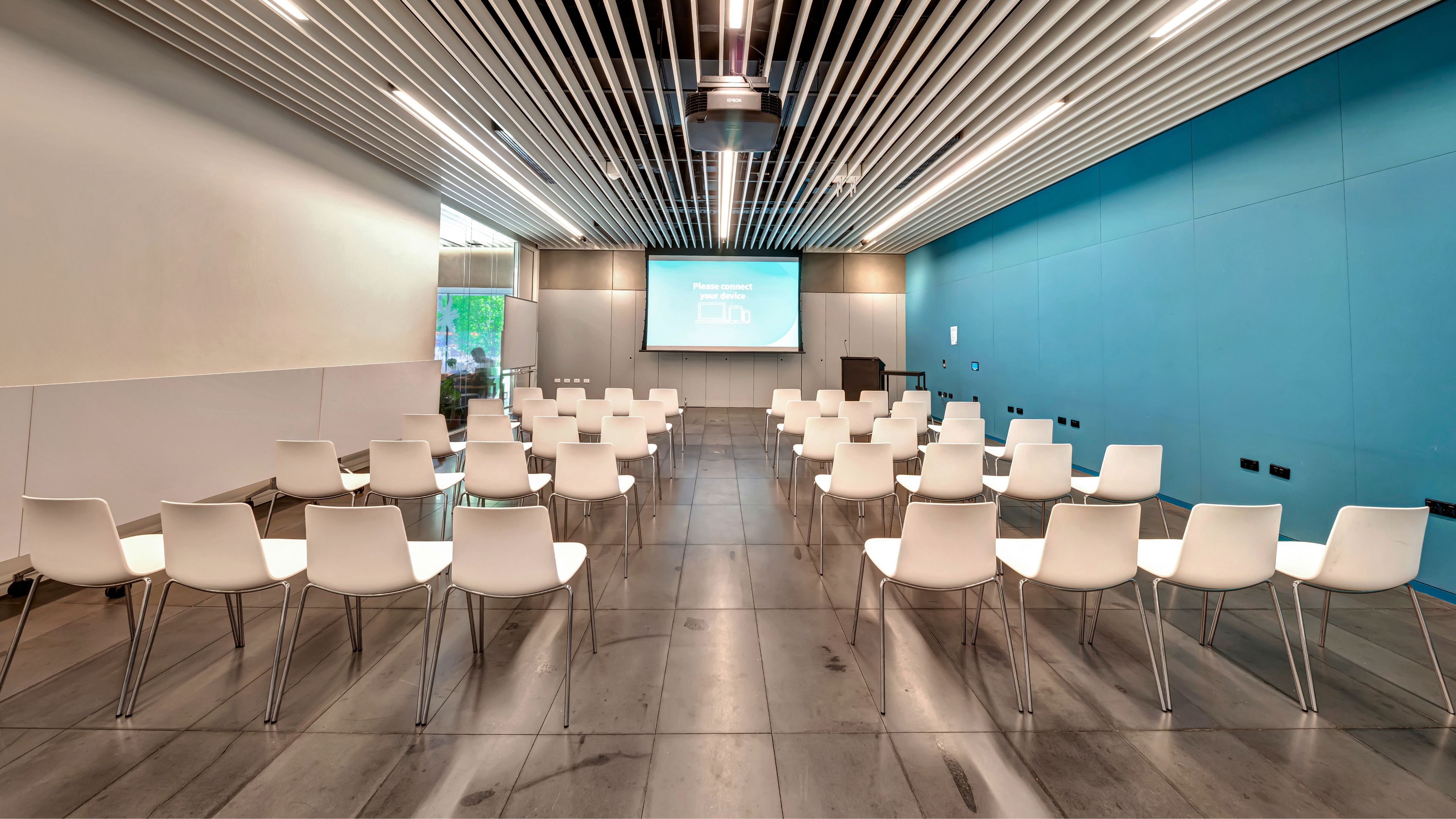 Conference room with white chairs in theatre layout and projected screen
