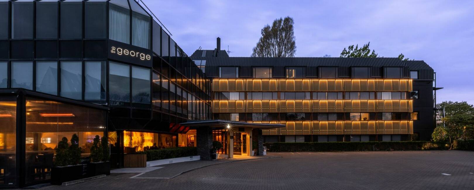 Multi-storey hotel building illuminated at dusk with warm interior lighting