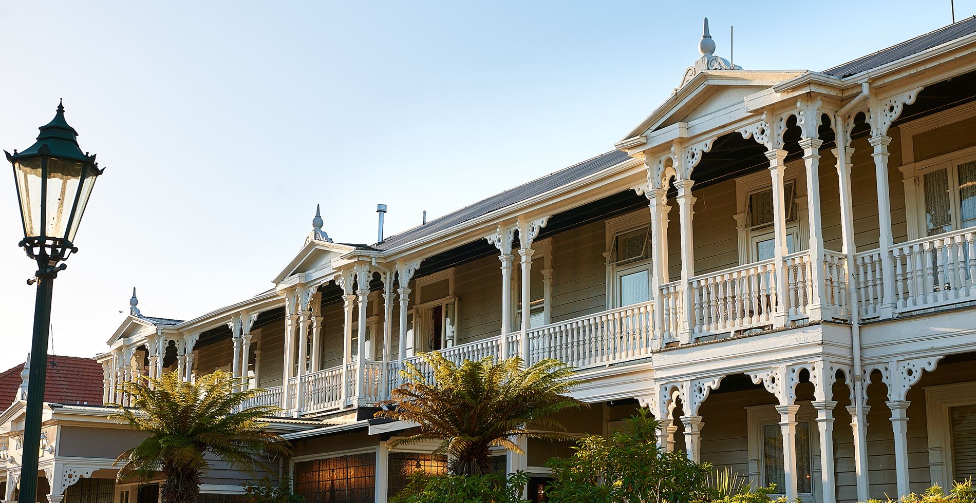 White two-storey Victorian-era hotel with ornate lacework verandahs, columns and decorative parapets