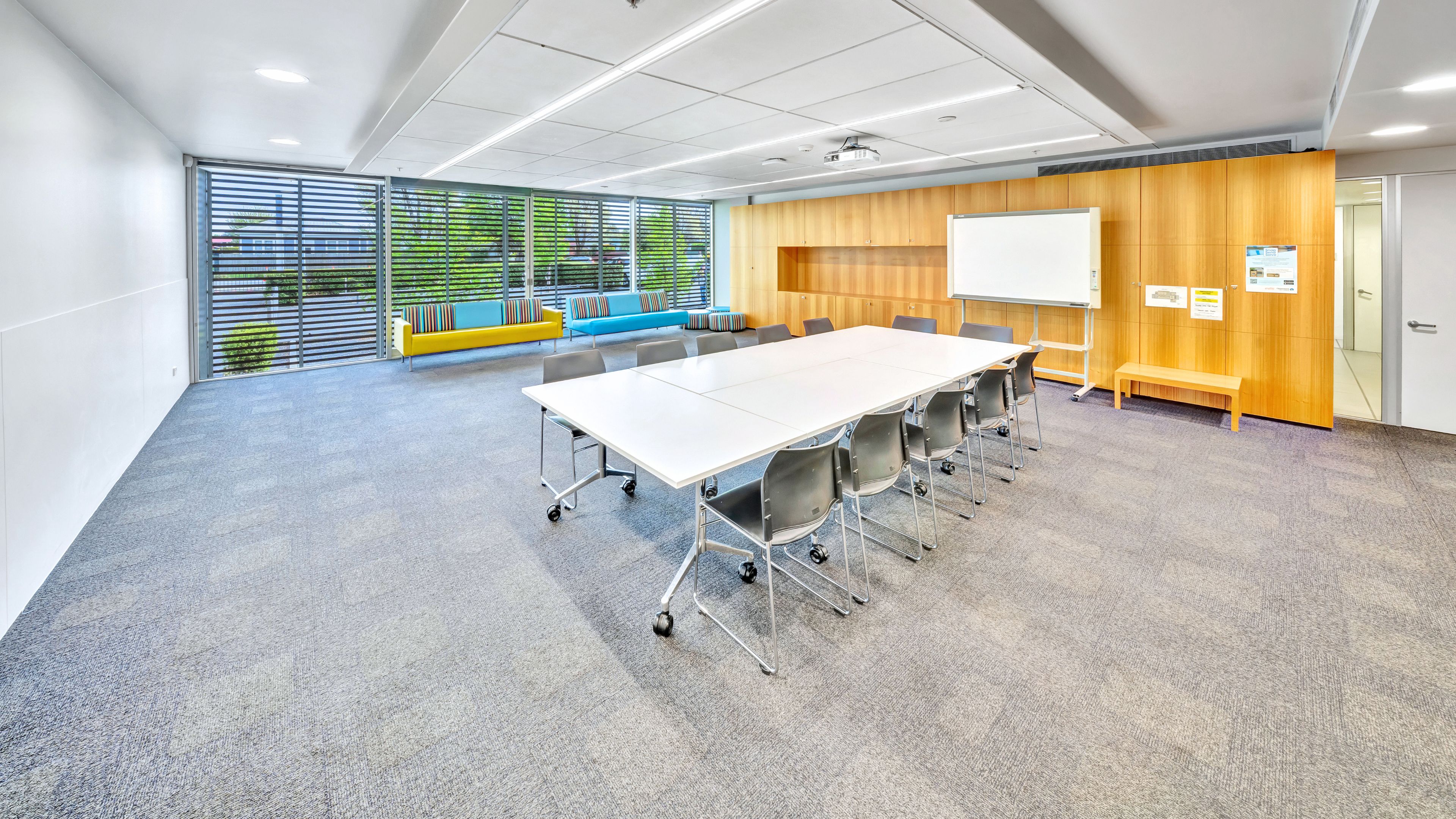 Meeting room with long table, chairs, whiteboard and timber wall panels