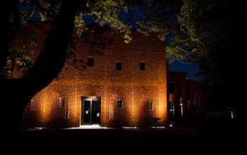 Red-brick college building illuminated at night from front entrance