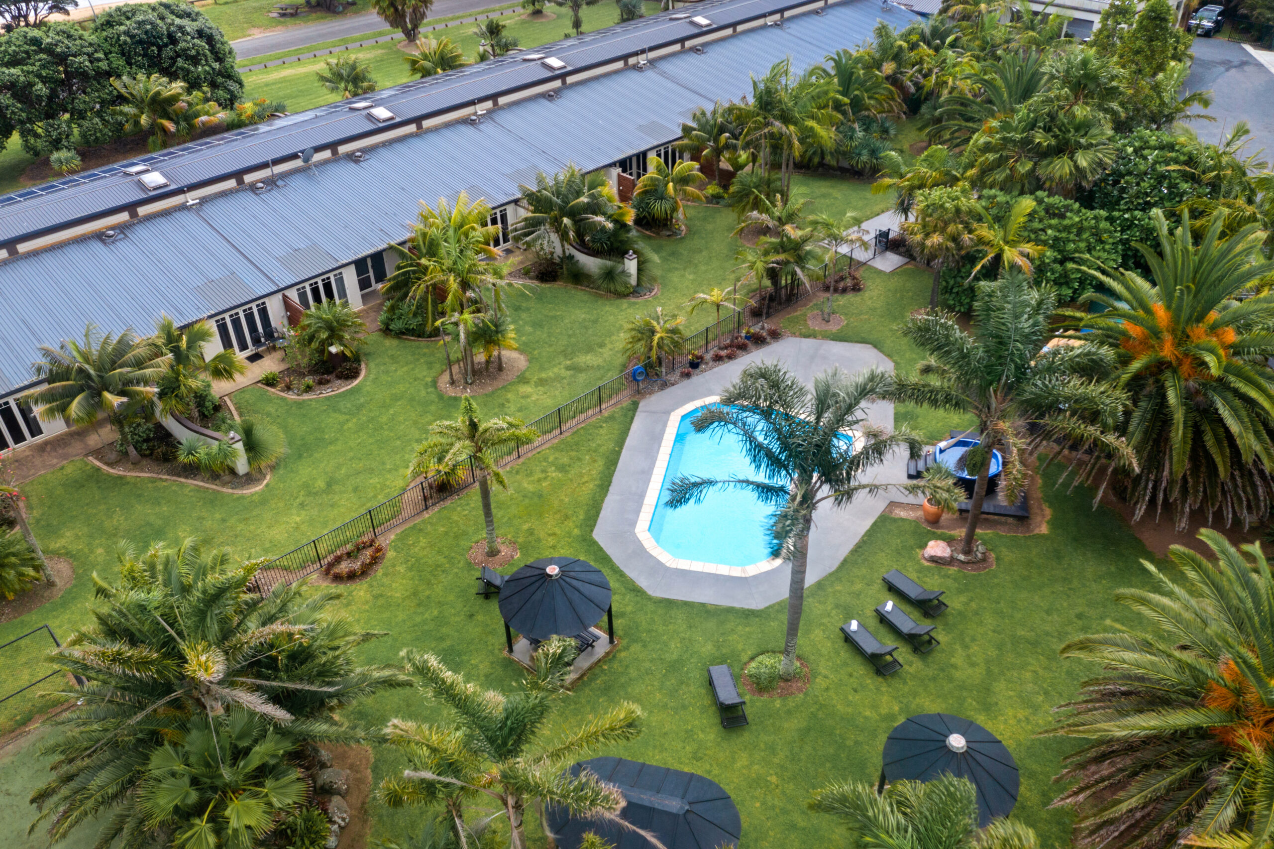 Aerial view of resort buildings, lawn, pool, and tropical plantings