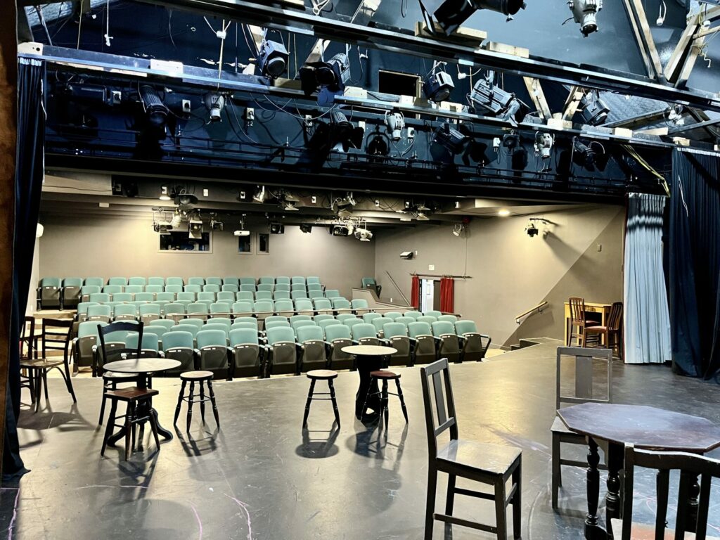 Theatre auditorium viewed from stage with tiered seating and stage lighting rigs