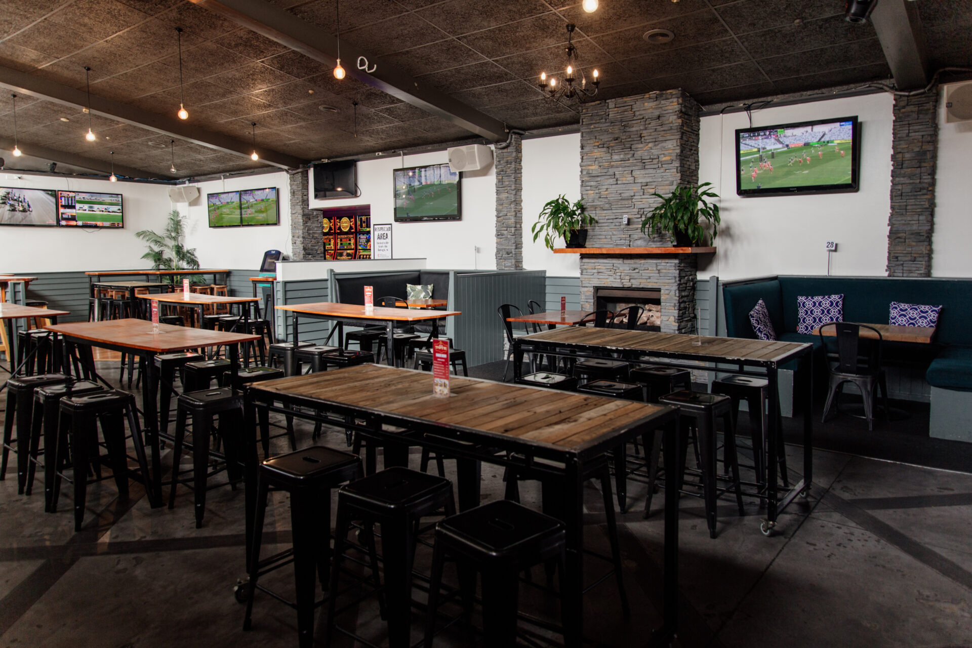 Outdoor courtyard with metal chairs and tables under pergola, venue signage on wall