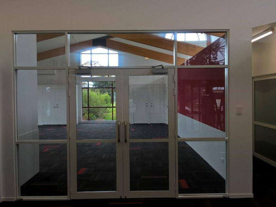 Glazed internal partition between two rooms with vaulted timber-beam ceiling beyond