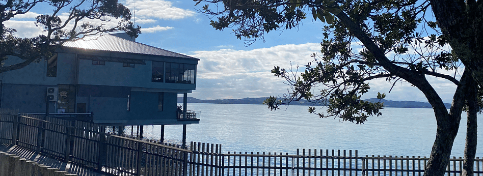 Club building on stilts over water with trees and hillside in background
