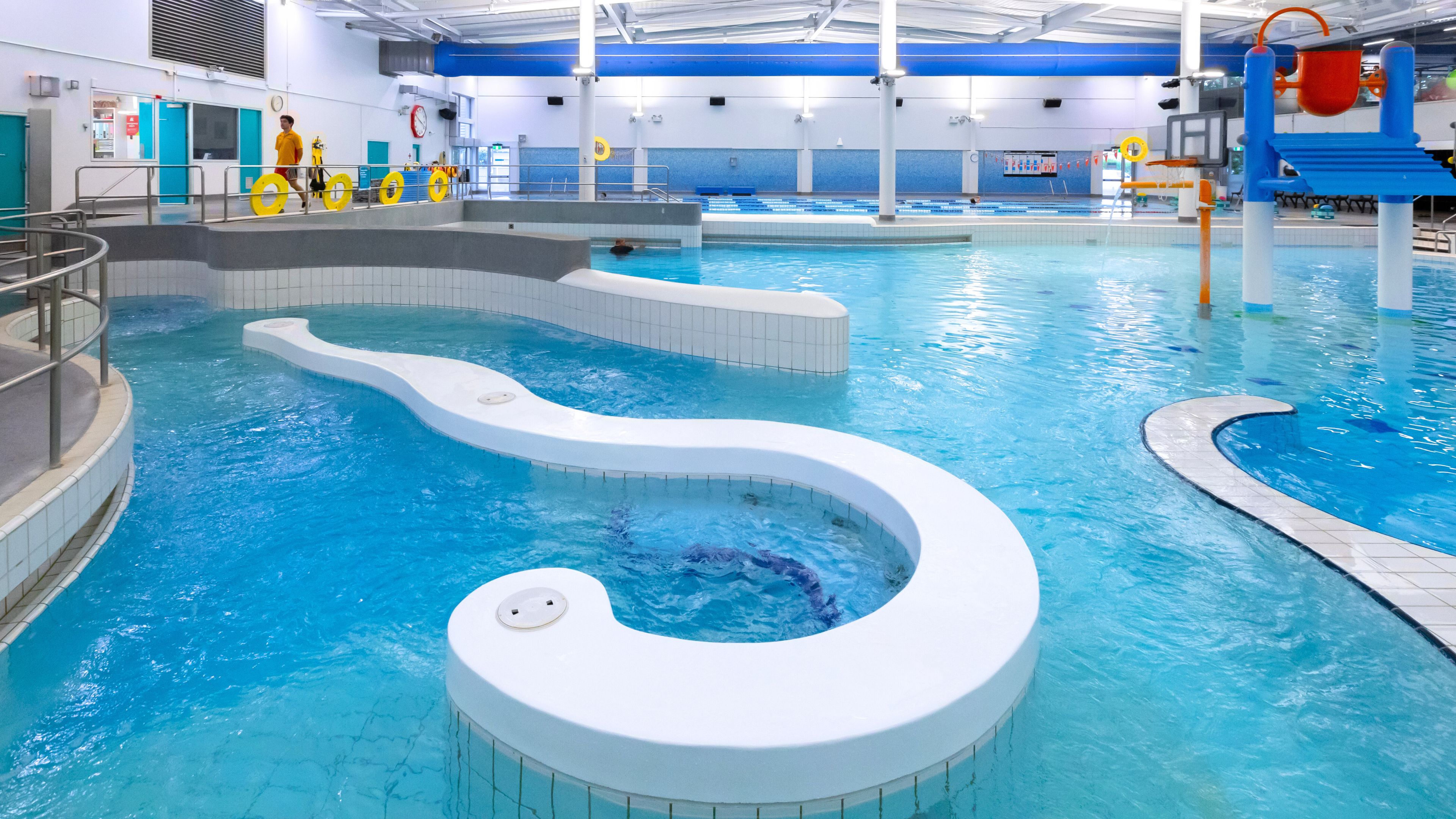Indoor pool with curved water feature, lazy river and play equipment