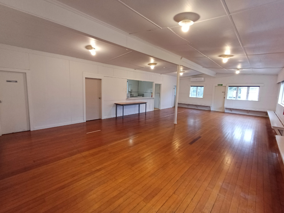 Open hall with polished timber floor and small kitchen servery opening