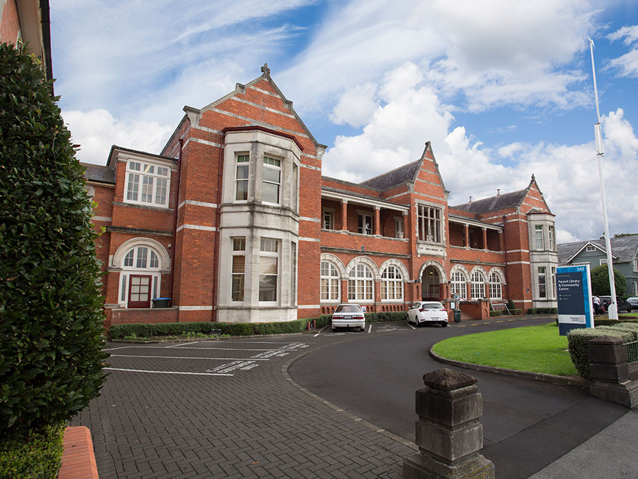 Two-storey red brick heritage building with gabled roofline, arched windows and circular drive
