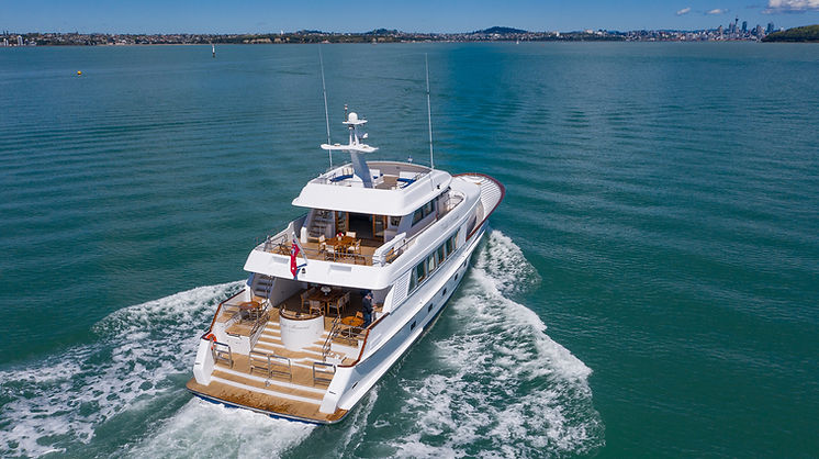 Large motor yacht underway in harbour with city skyline in background