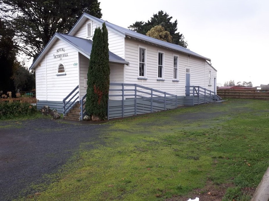White weatherboard hall exterior with blue-grey ramp and stairs, lawns and trees