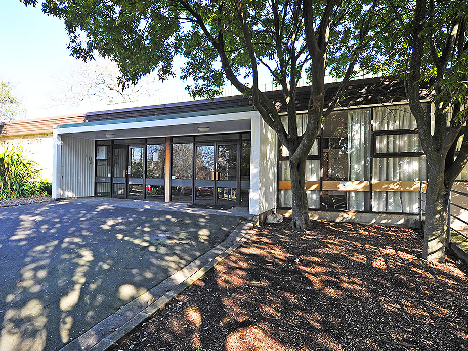 Low flat-roofed building with large windows and landscaped forecourt