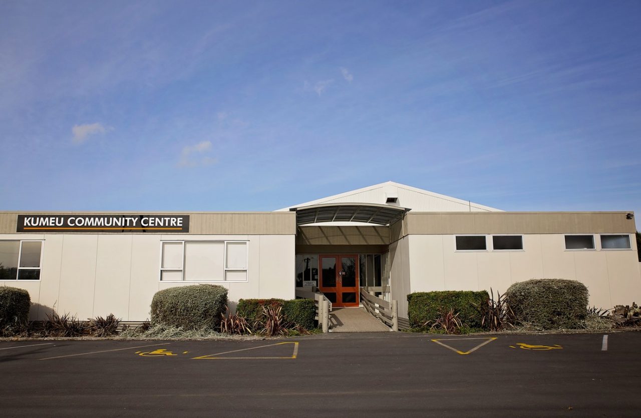 Single-storey community centre building with car park in foreground