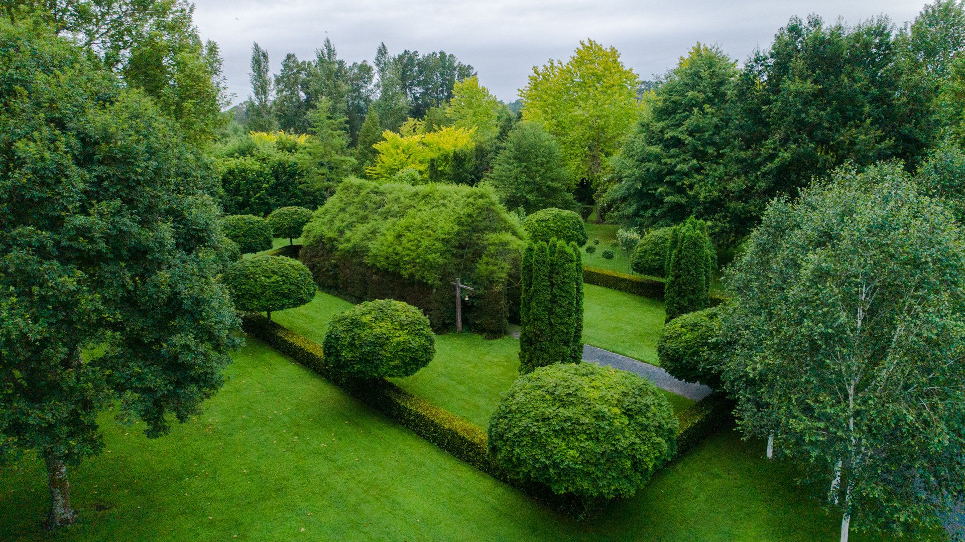 Aerial view of clipped green topiary garden with a living hedge structure amid lawns and trees