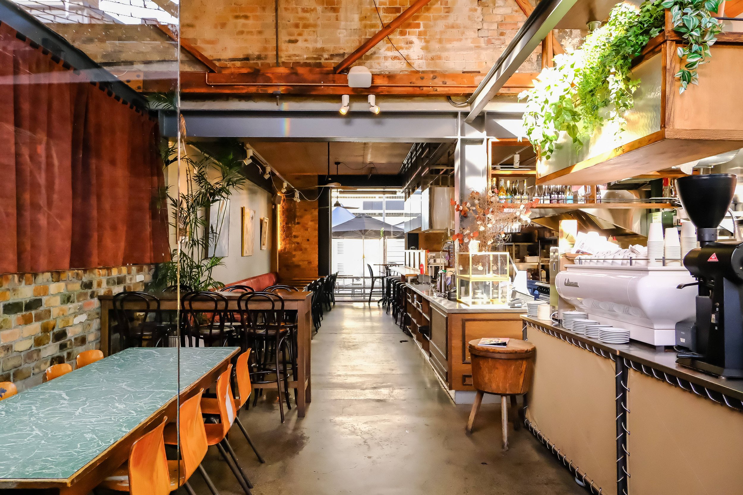 Industrial cafe interior with exposed brick, concrete floor, hanging plants, bar counter and seating