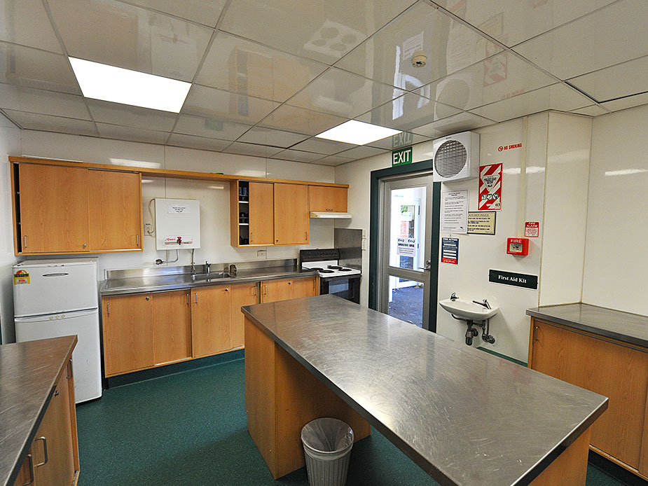 Community hall kitchen with timber cabinets, stainless steel benchtops and exit door