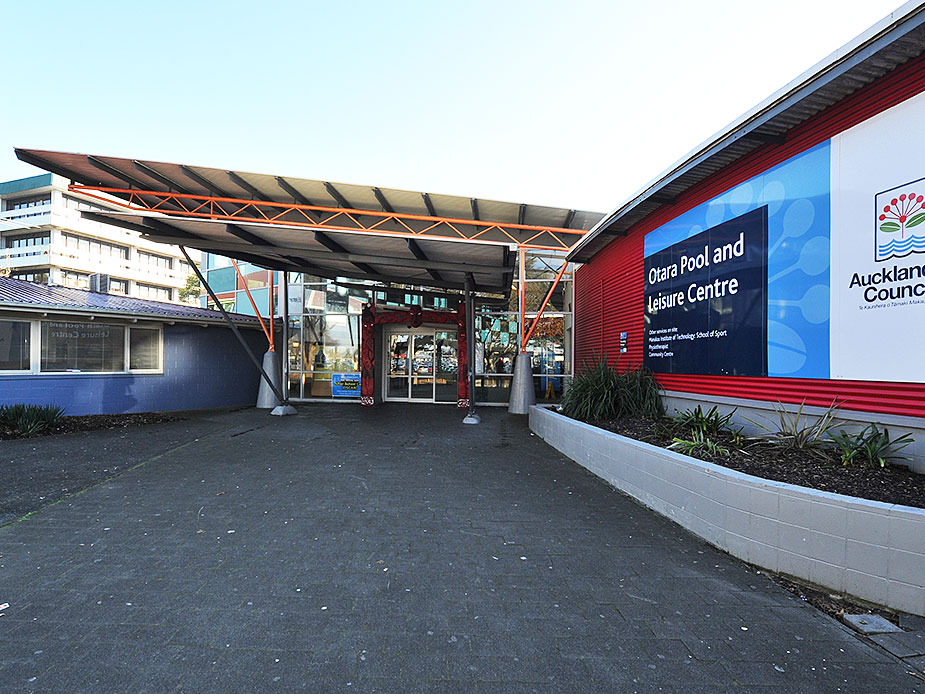Red and blue painted building exterior with covered entrance canopy, carpark setting