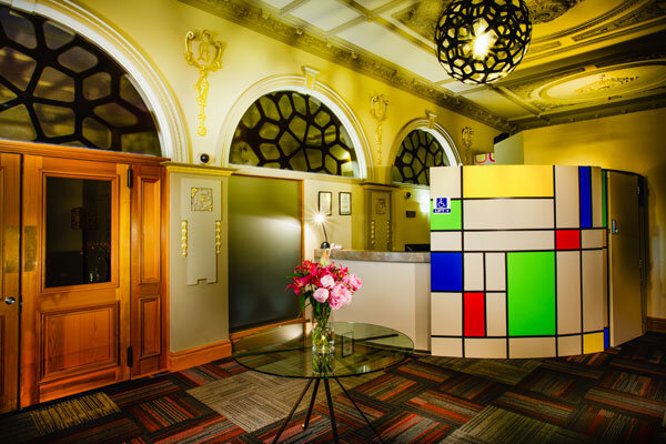 Heritage foyer with plaster arches and cornices, colourful geometric reception desk
