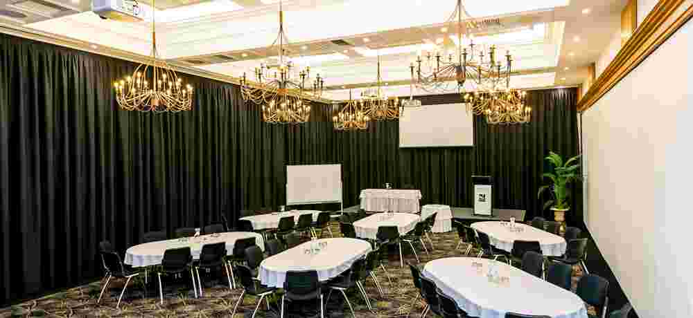 Function room with oval tables, chandelier lighting and dark drapes