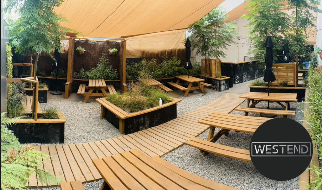 Outdoor beer garden with timber benches, raised planting beds and shade sails