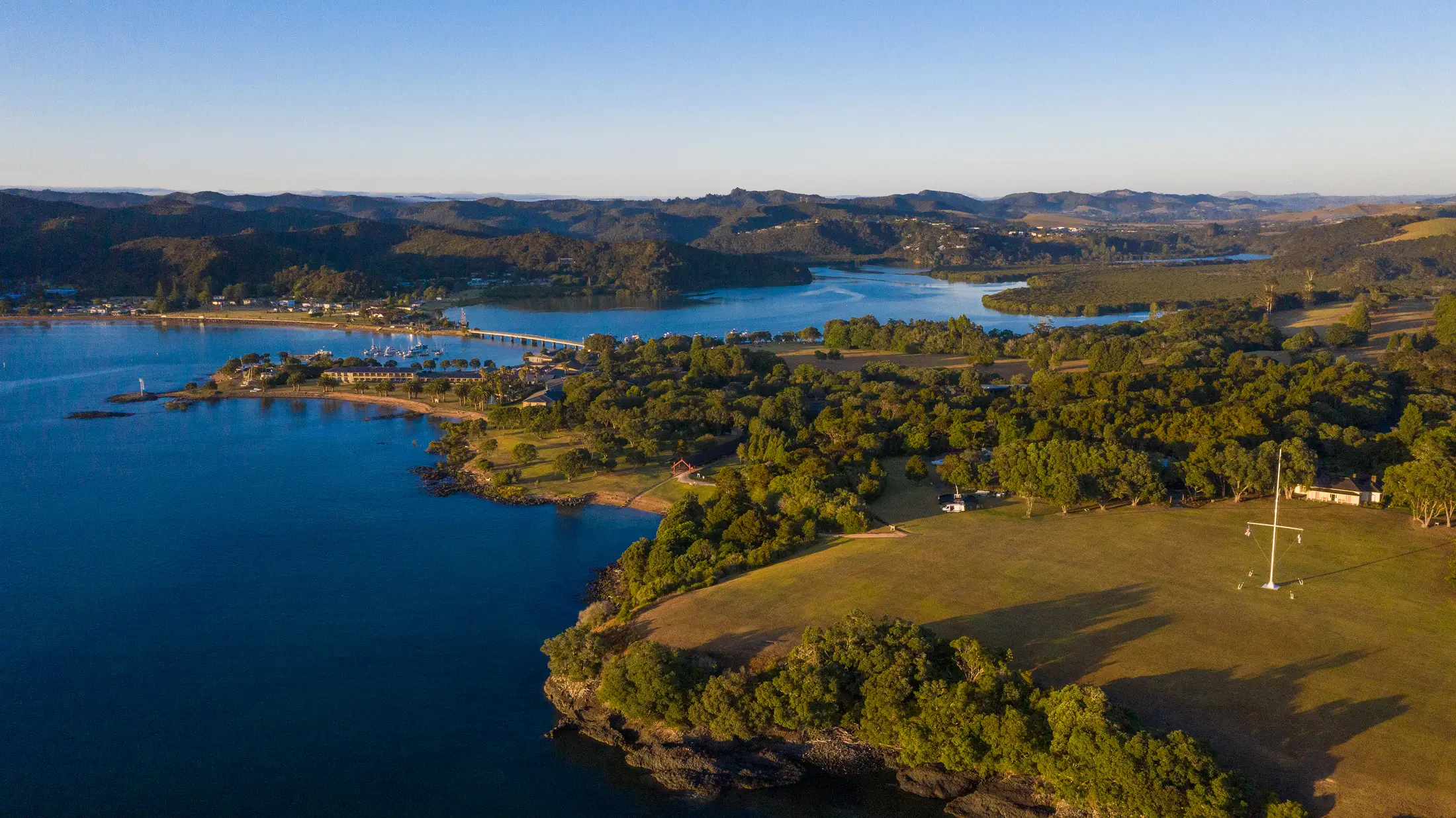 Aerial view of Waitangi Treaty Grounds on a bay peninsula surrounded by water and trees
