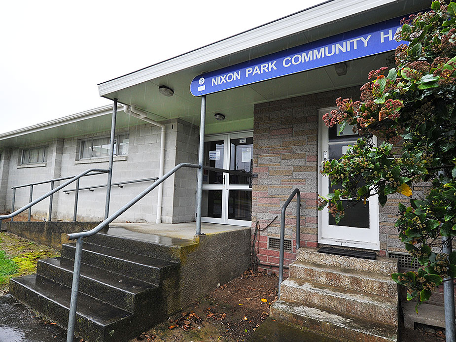 Community hall exterior with brick entrance, signage and glazed door in rain