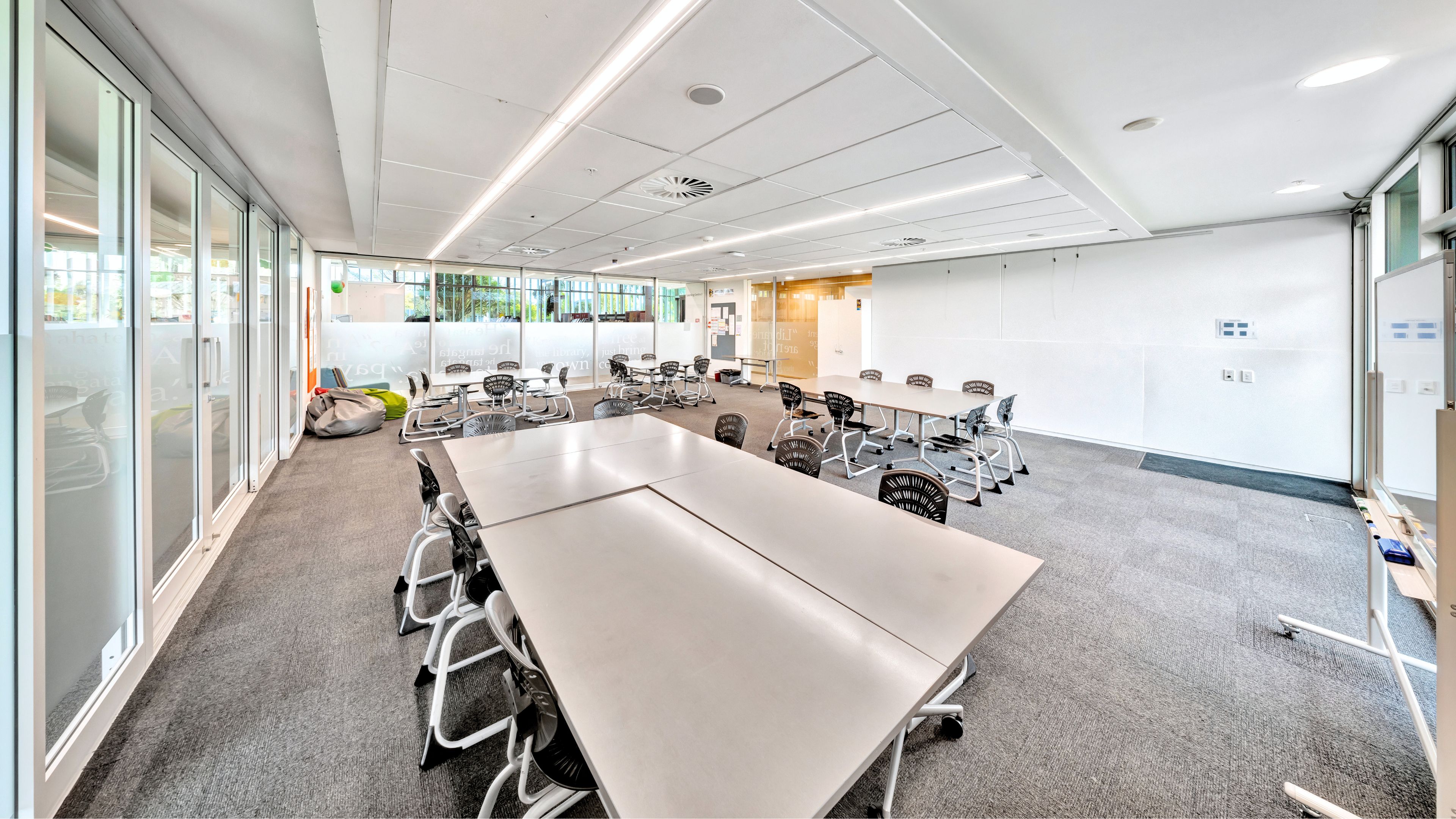 Flexible room with tables and chairs in open layout, whiteboard on wall