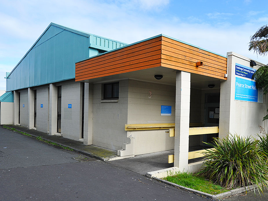 Low community hall exterior with teal metal roof and timber cladding canopy