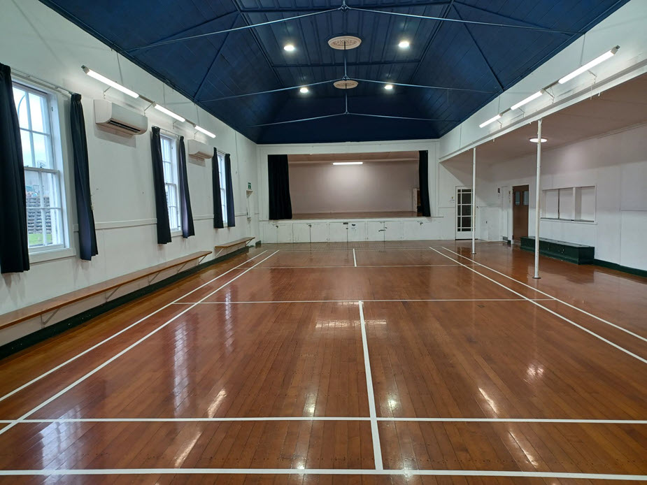 Hall main space with polished timber floor, blue ceiling and stage