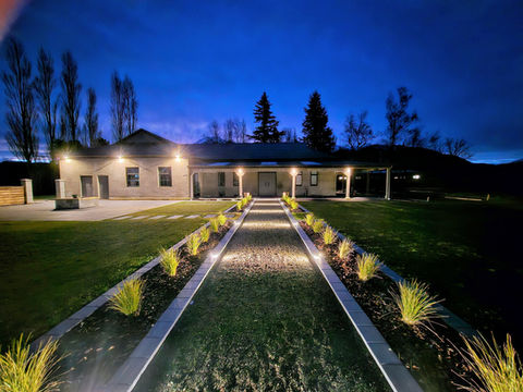 Venue entrance at dusk with lit pathway, plantings, and mountain view