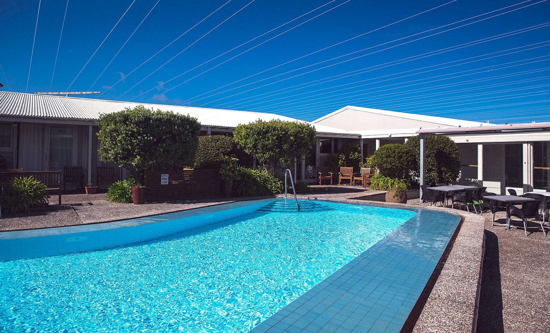 Outdoor swimming pool with garden and motel buildings surrounding it
