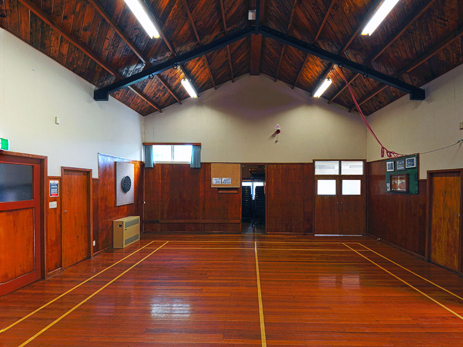 Hall interior with timber ceiling trusses, polished floor, and timber wainscoting