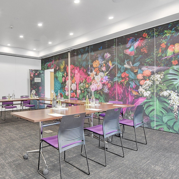 Meeting room with tables, chairs, and bold floral wallpaper mural