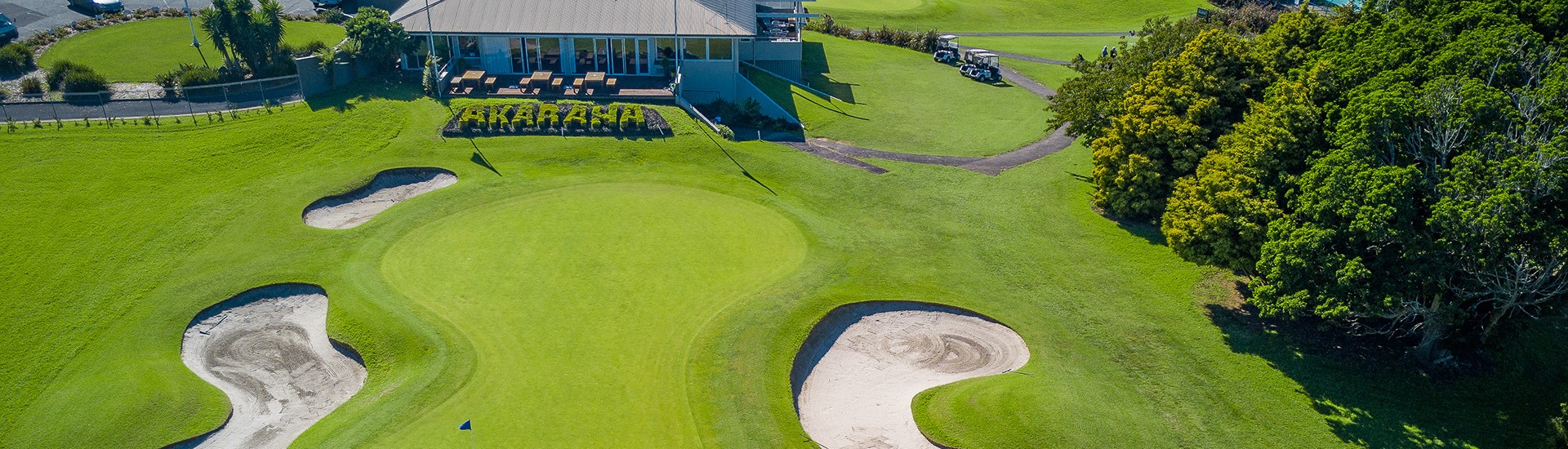 Aerial view of Akarana Golf Club clubhouse and course with sand bunkers and a topiary hedge spelling the club name