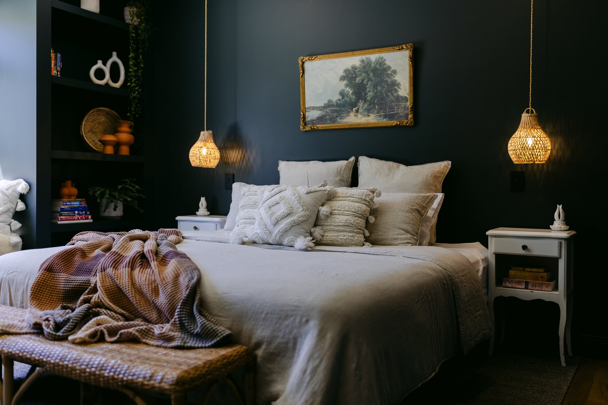 Styled bedroom with dark walls, pendant lights and framed artwork
