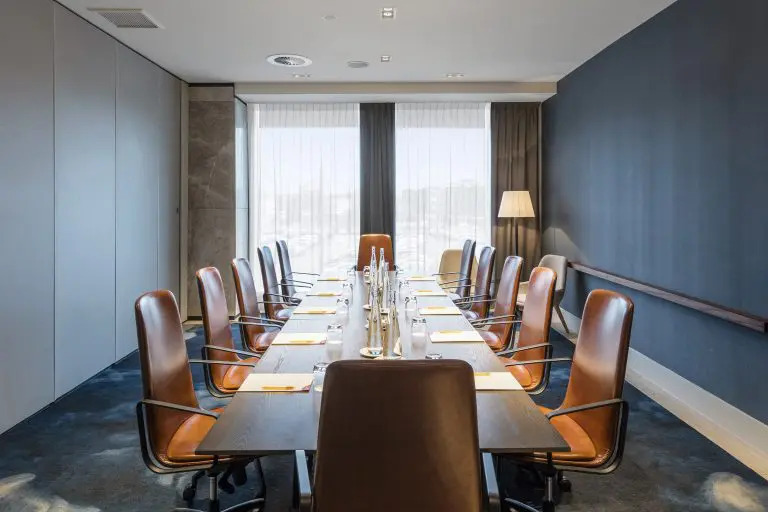 Hotel boardroom with long table, leather chairs, and large windows
