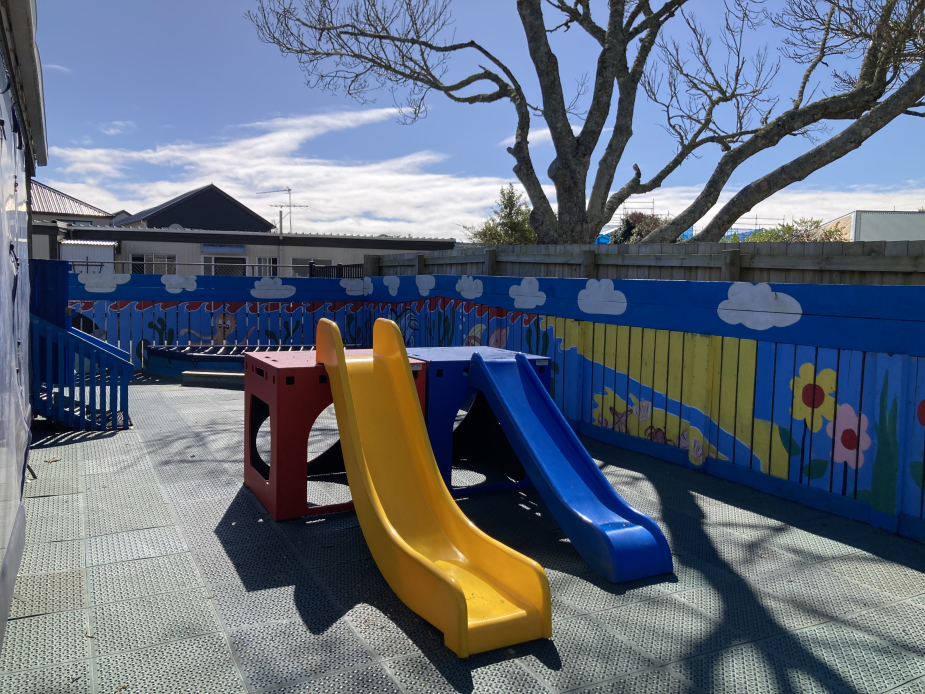 Outdoor playground with colourful slides and painted fence