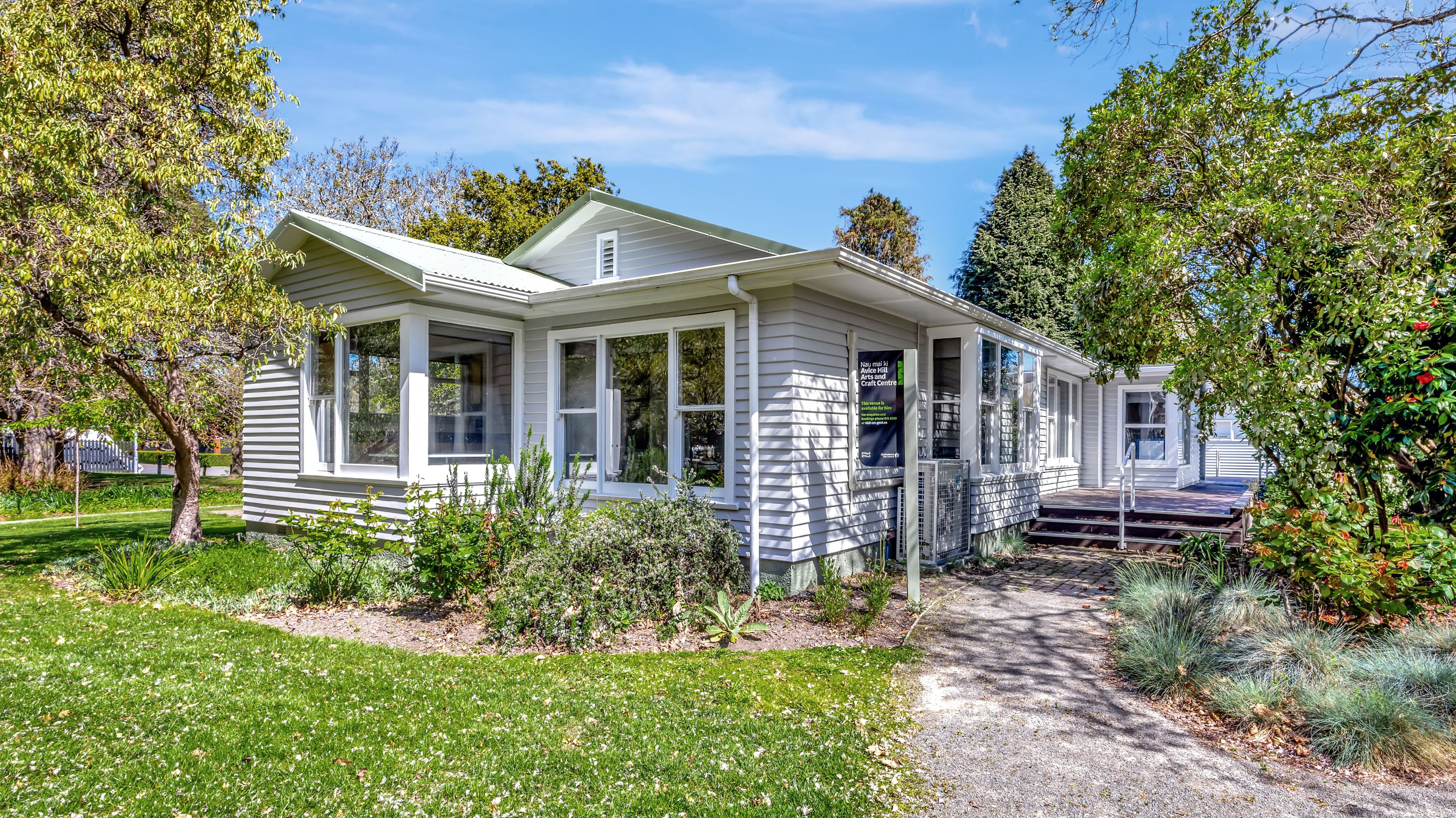 Single-storey weatherboard building with garden surrounds and entry steps