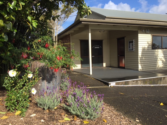 Cream weatherboard hall with covered entry porch, mixed garden planting in foreground
