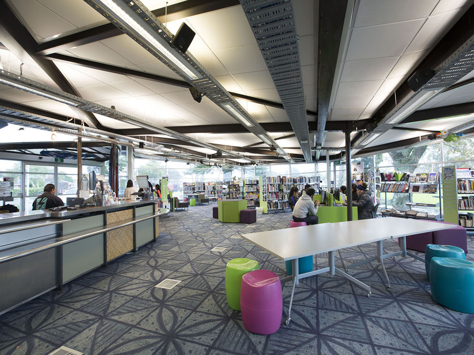 Open-plan library interior with colourful seating, bookshelves and patterned carpet