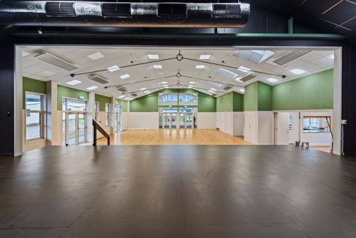 Hall interior viewed through roller door opening, green walls and timber floor