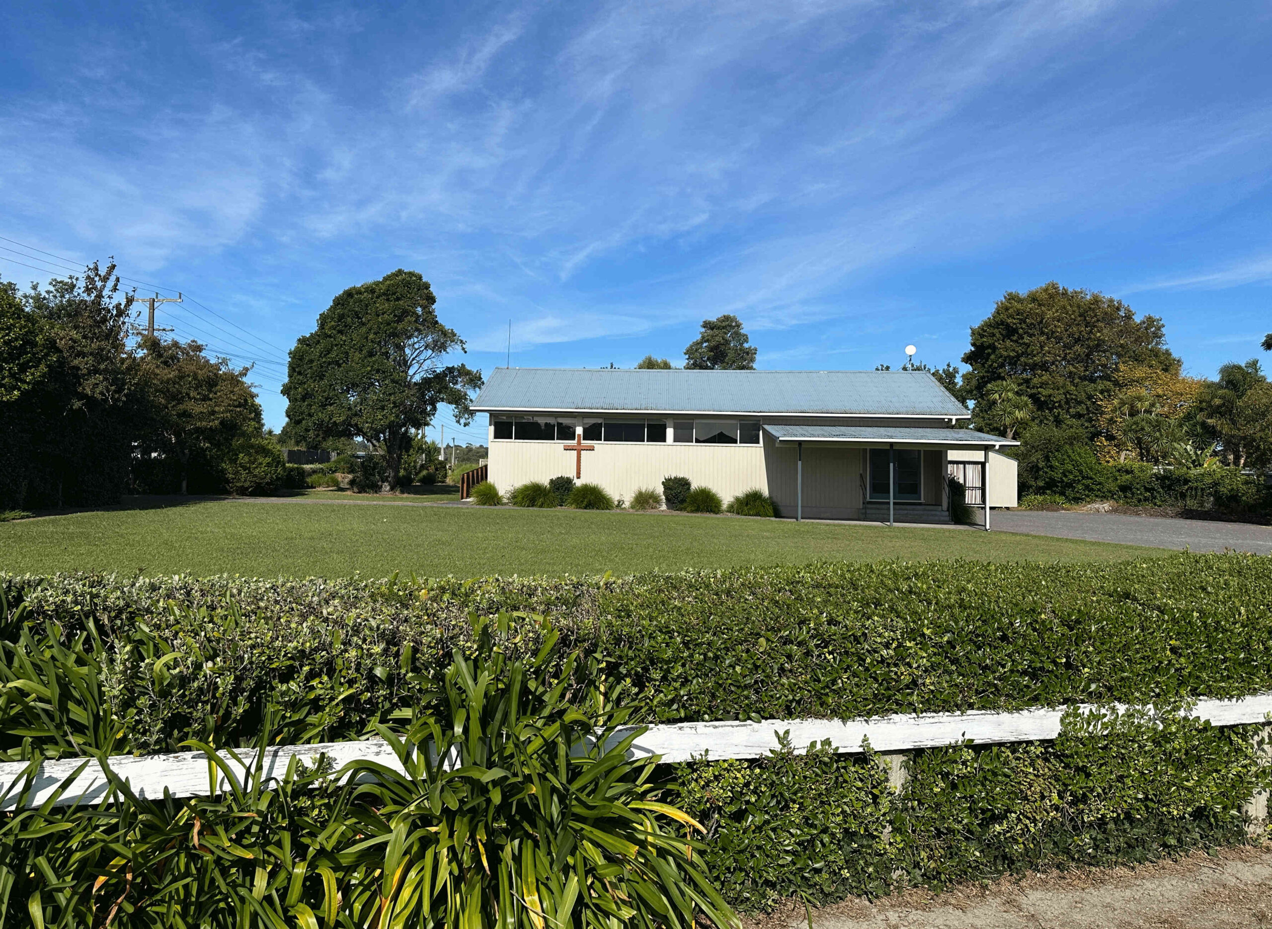 Dark grey church building with large signage reading Helensville Community Church and cross on roofline