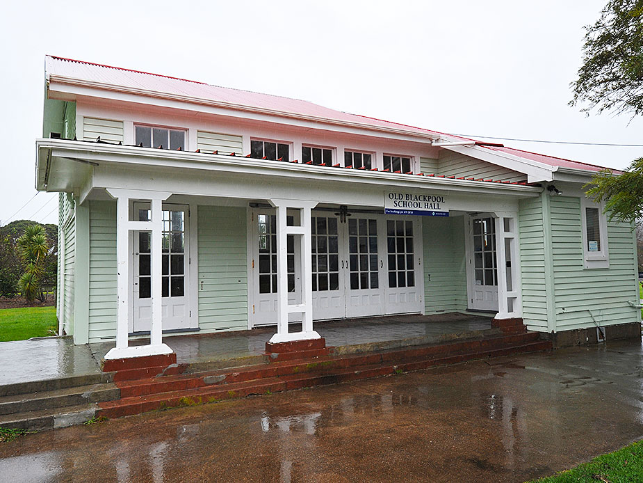 White timber hall with covered veranda, French doors, and red iron roof, wet forecourt