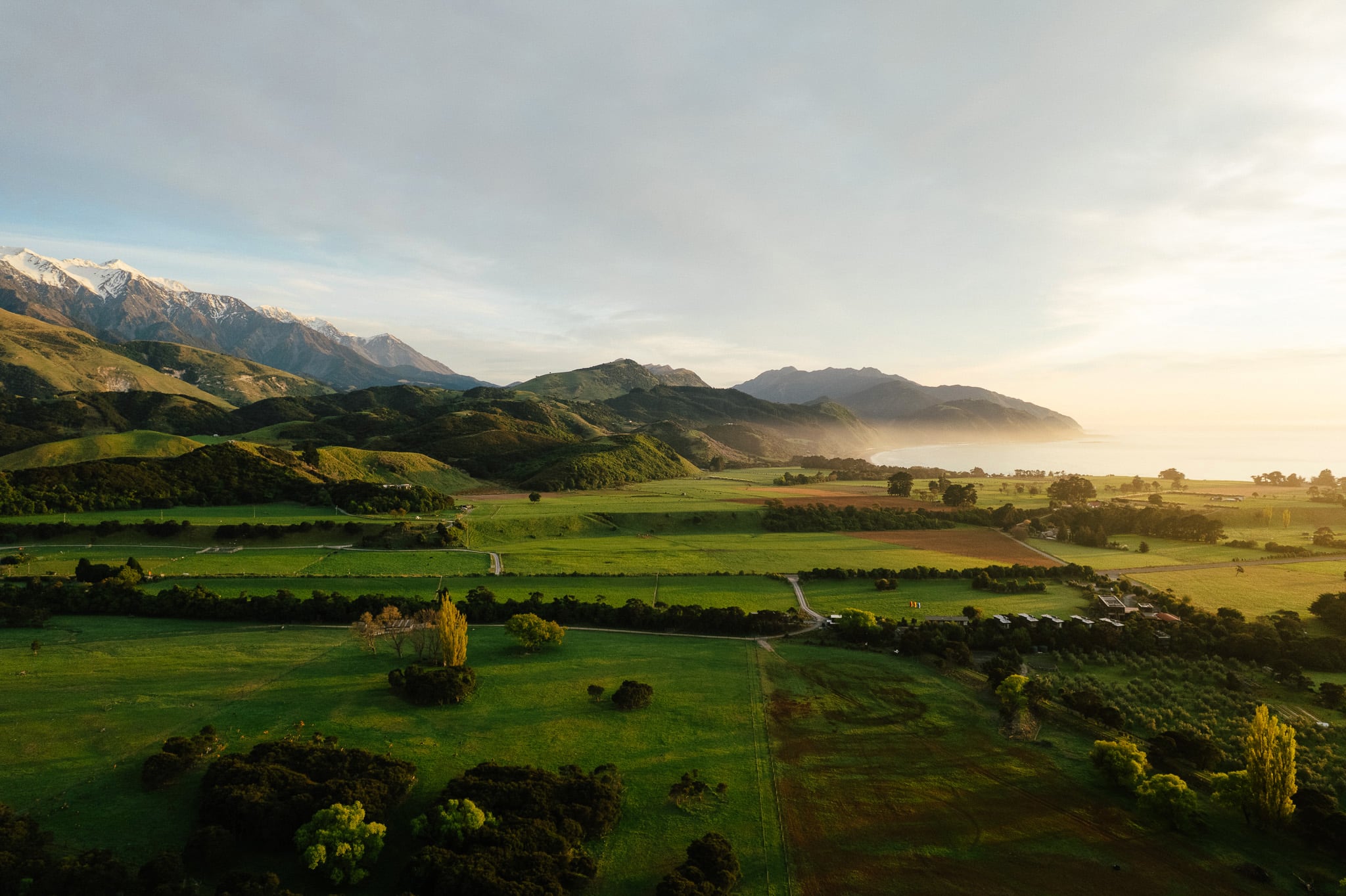 Aerial view of rural valley with farmland, mountains, and coastline