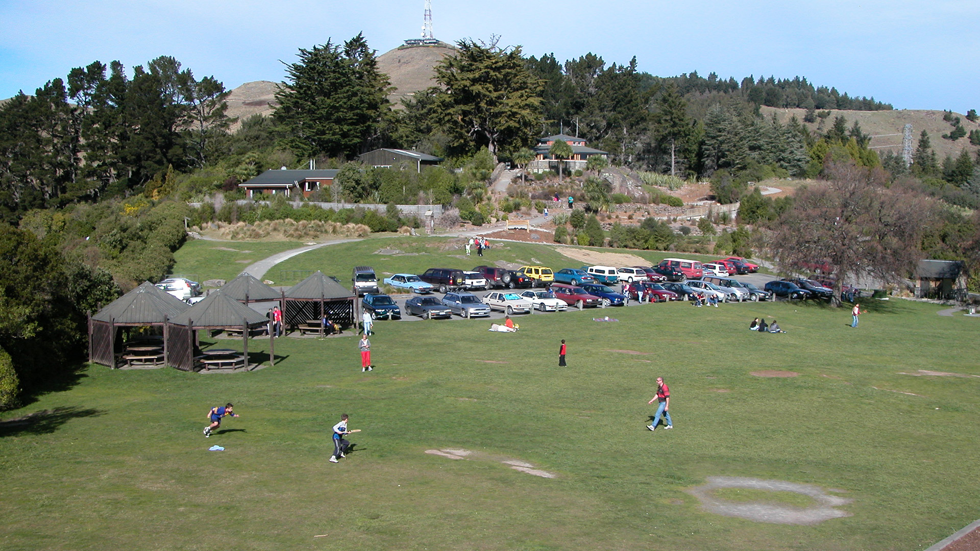 Open park area with lawn, pavilion shelters and hillside in background