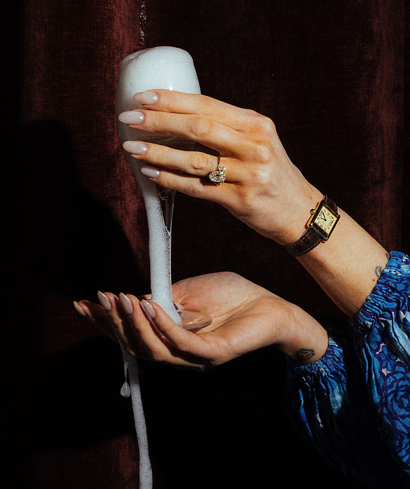 Close-up of hands holding a foaming champagne flute with a ring visible