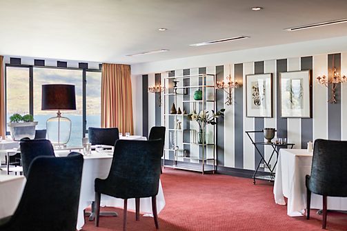 Restaurant dining room with striped feature wall, round tables and lake view through window